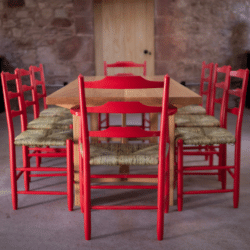 Wooden Dining table with eight red Chairs from The Marchmont Workshop. An exhibitor at Craftworks.